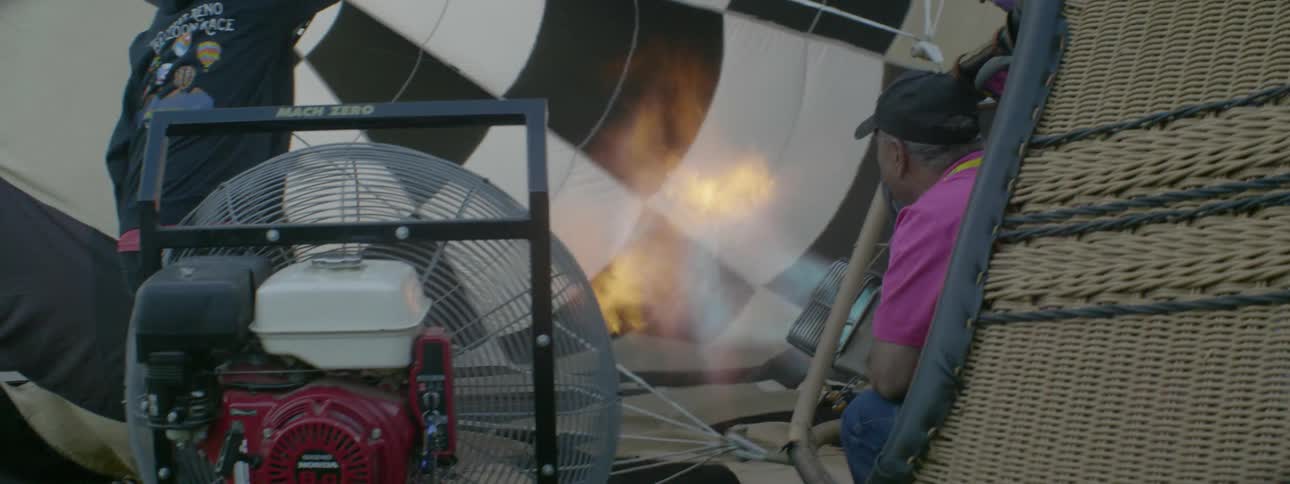 A man is blowing up his hot air balloon