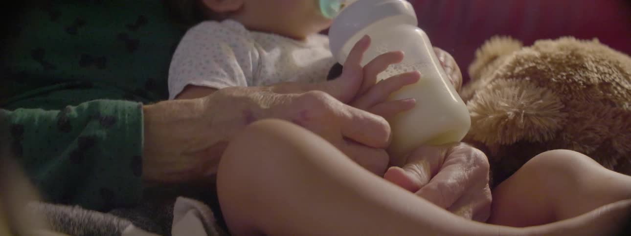 An old person is rubbing a baby's hand during the day