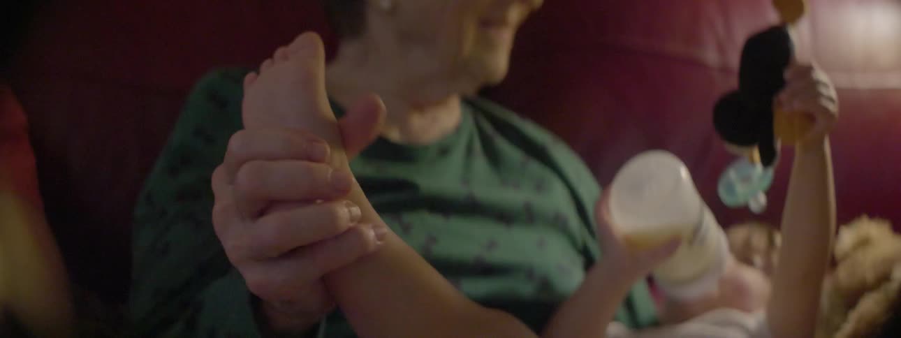 An old woman is holding and rubbing a baby's foot
