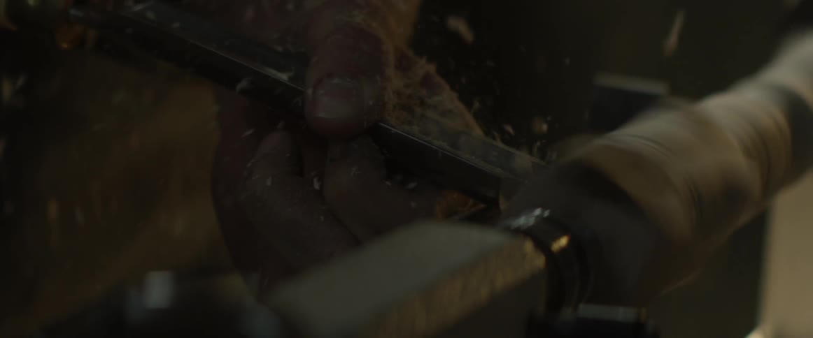 A man shapes a piece of wood on a lathe