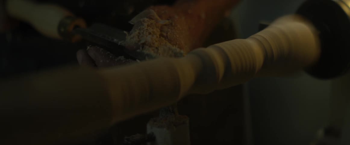 A man shapes a piece of wood on a lathe