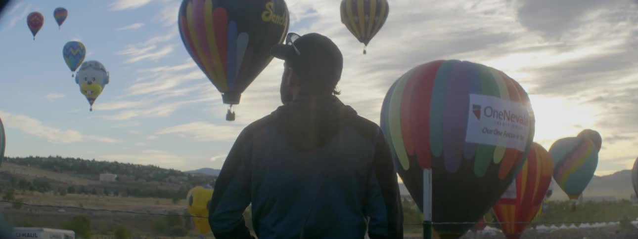 A man watches hot air balloons rise and fly