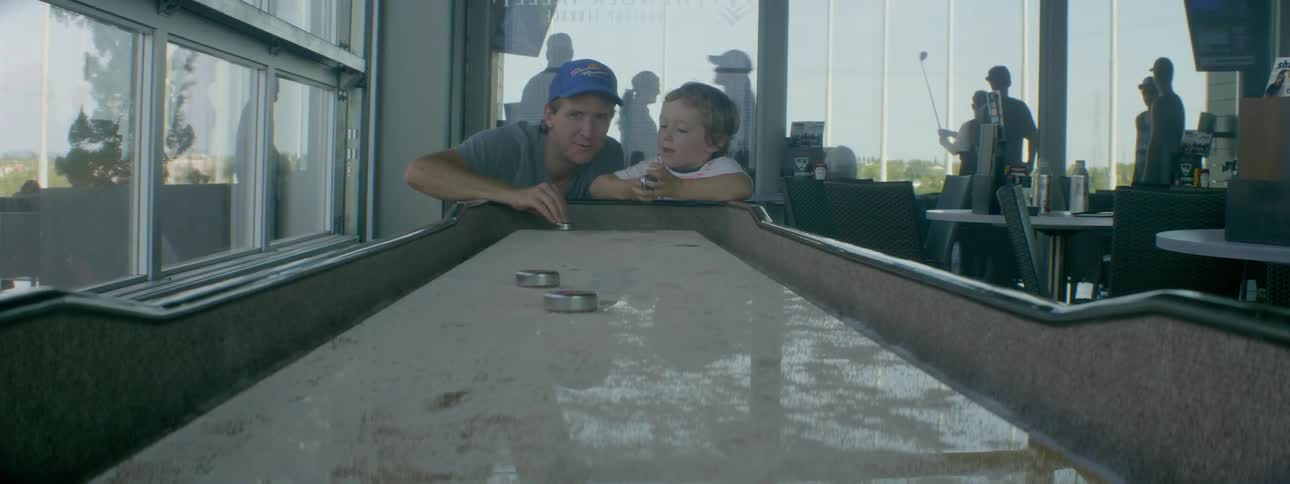 A father and son play an arcade size curling game
