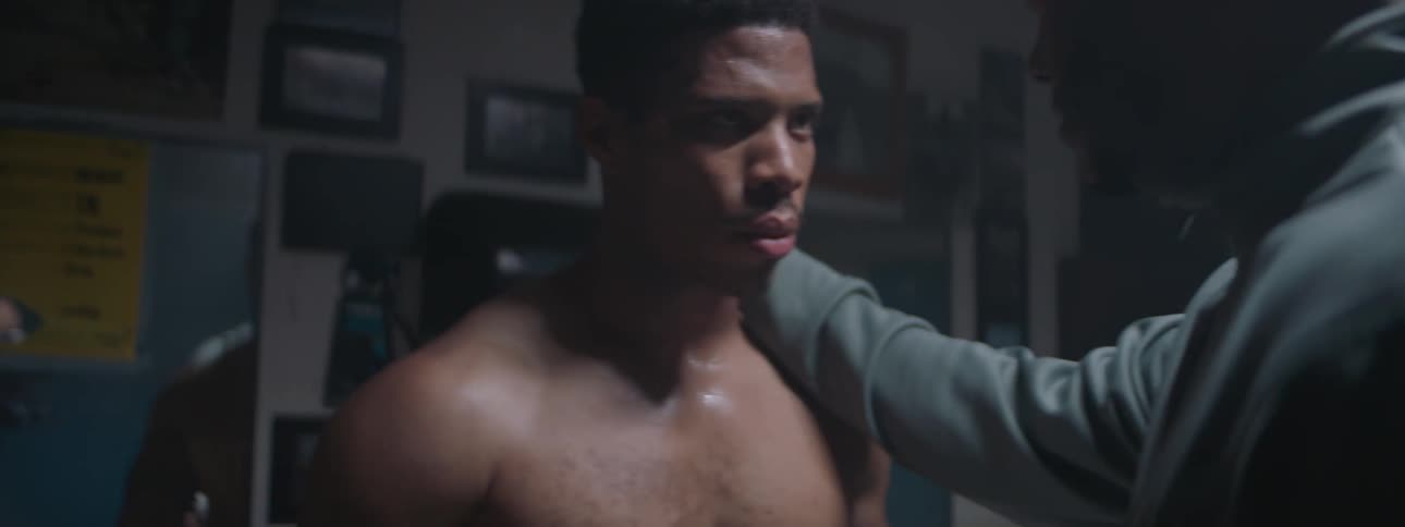 A man wearing boxing gloves talks with his coach
