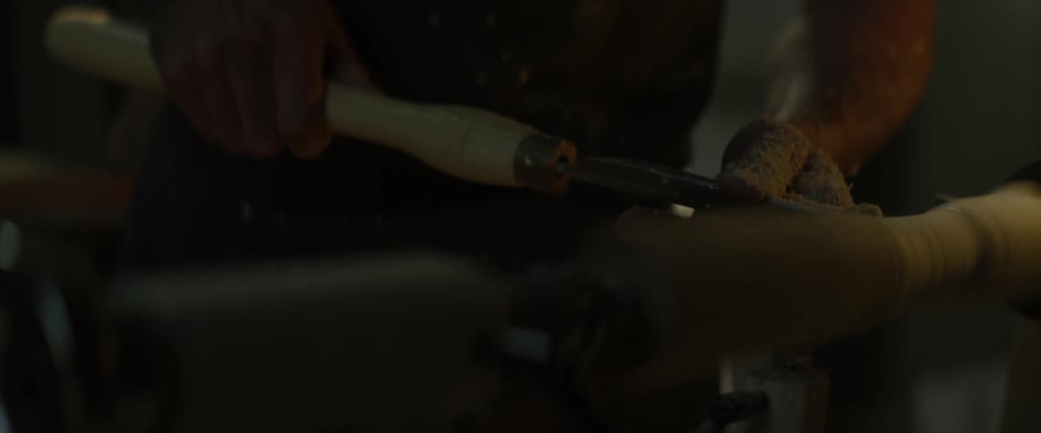 A carpenter carves a spinning piece of wood
