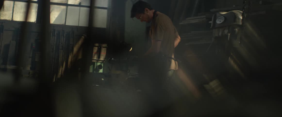 A man is using a lathe in a warehouse during the day