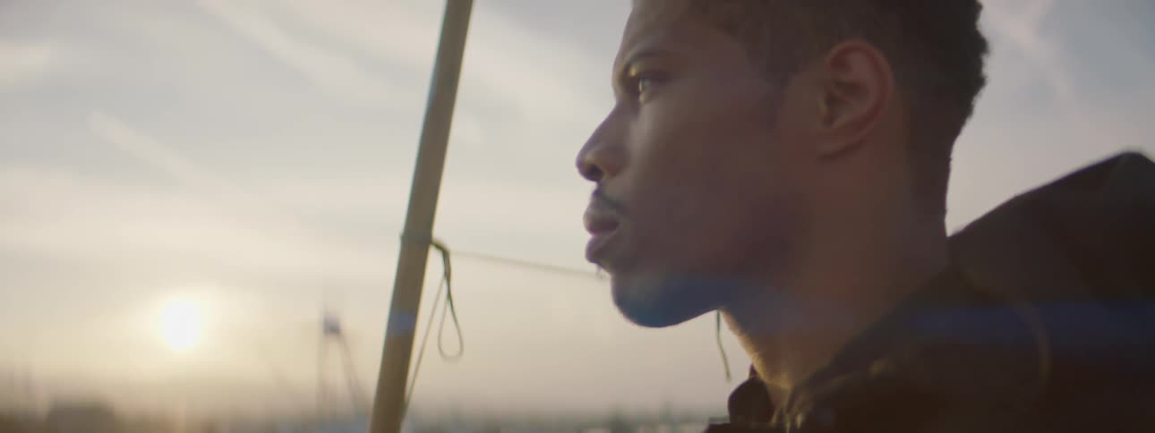 A man stands outside at sunset