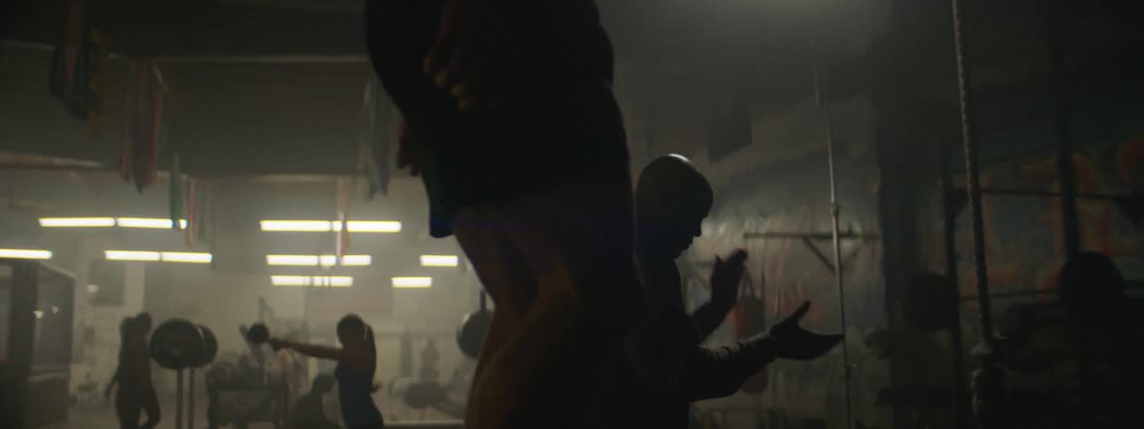A coach is encouraging an athlete as he trains in a gym
