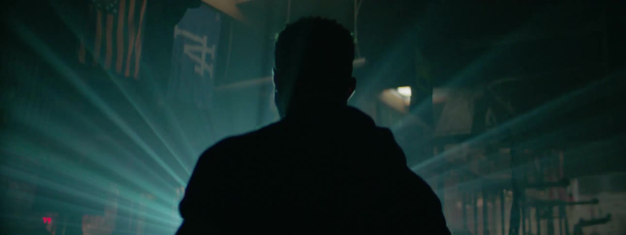 An athlete is standing facing a shining light at night