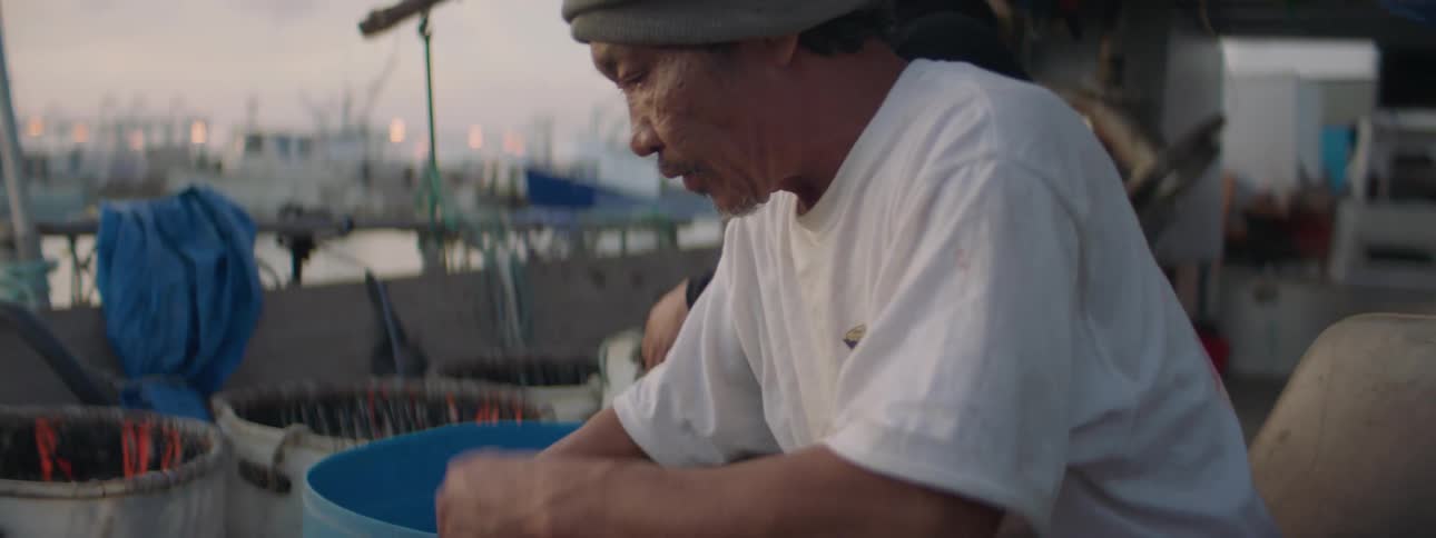 Two men handle ropes on a boat