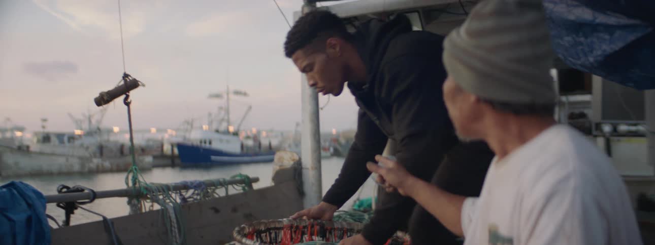 Two men load barrels onto a boat