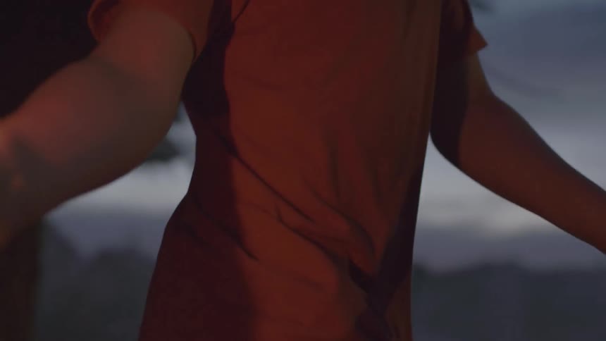 A white teenager runs through nature with a lit firework in his hand