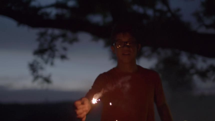 A boy runs with a smoking sparkler