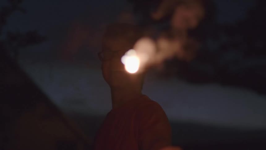 A boy holds a smoking sparkler