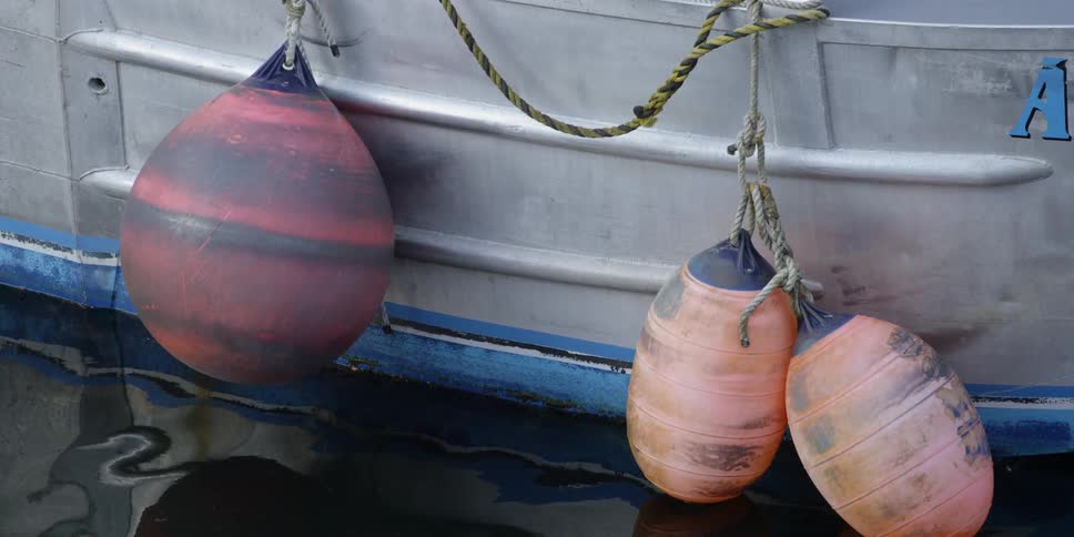 Fishing buoys hang of the side of a boat during the day