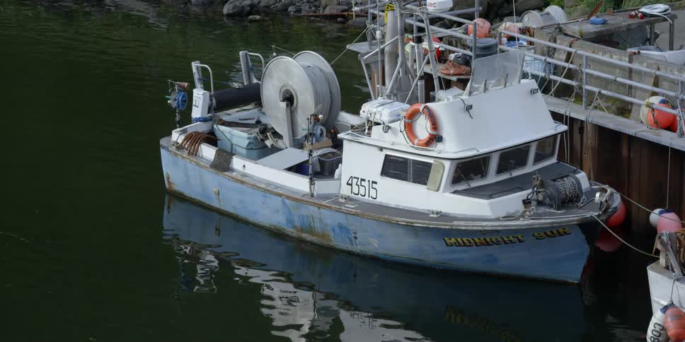 A fishing boat is sitting docked at a pier during the day