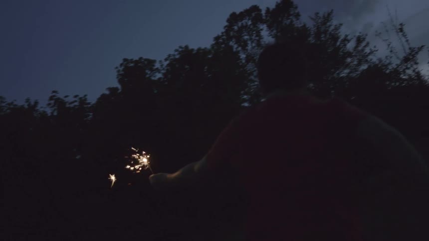 A person running in the dark with sparklers