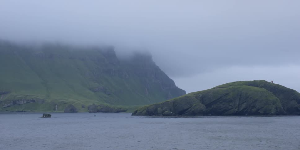 Fog hangs above the water and mountain