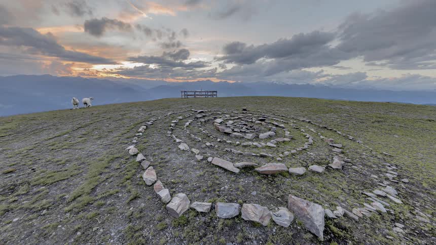 Clouds pass above a spiral rock arrangement atop a hill