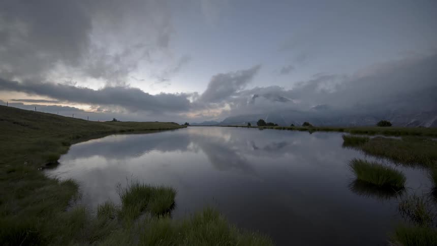 Clouds pass over a lake at sunrise