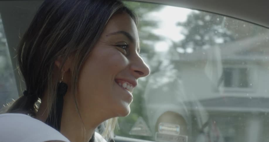 A woman laughs as she drives a car