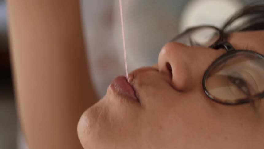A girl in glasses is playing with her bubble gum