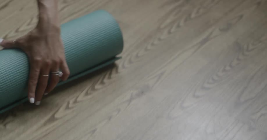 A woman rolls up a green yoga mat