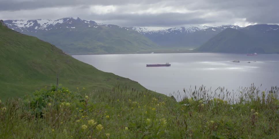 A large ship is sailing across the ocean from an island