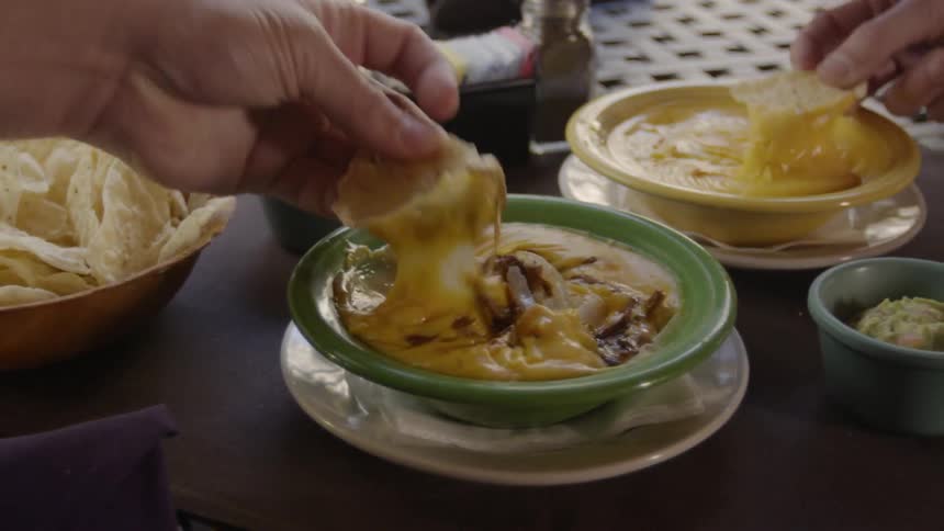 People are using chips to scoop up dip at a restaurant table