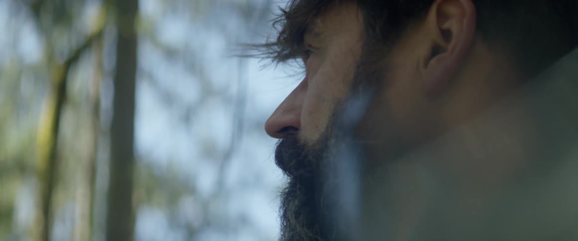 A man is standing in a forest staring on a sunny day