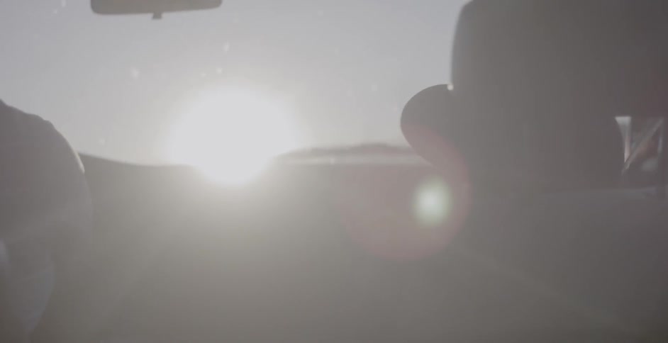 A man and boy ride in a car on a sunny day