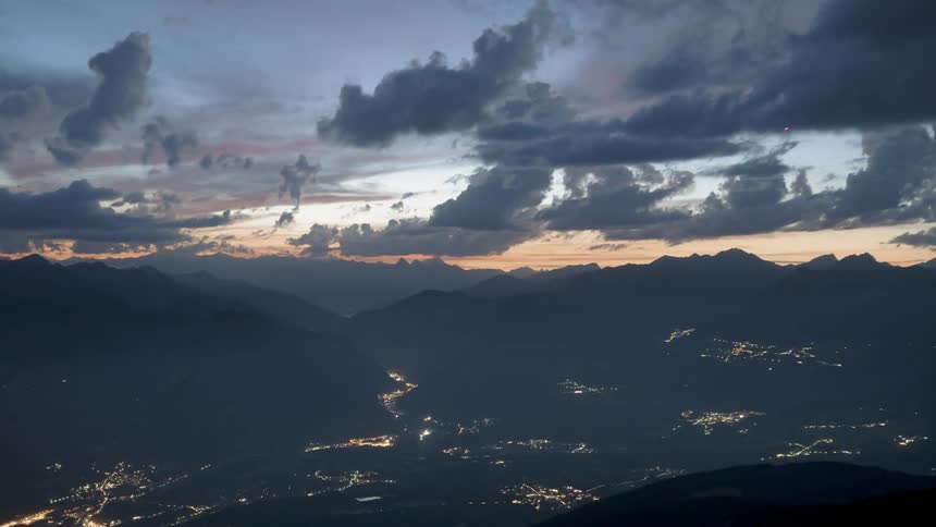 Clouds hang and float over the city at the bottom of the hills