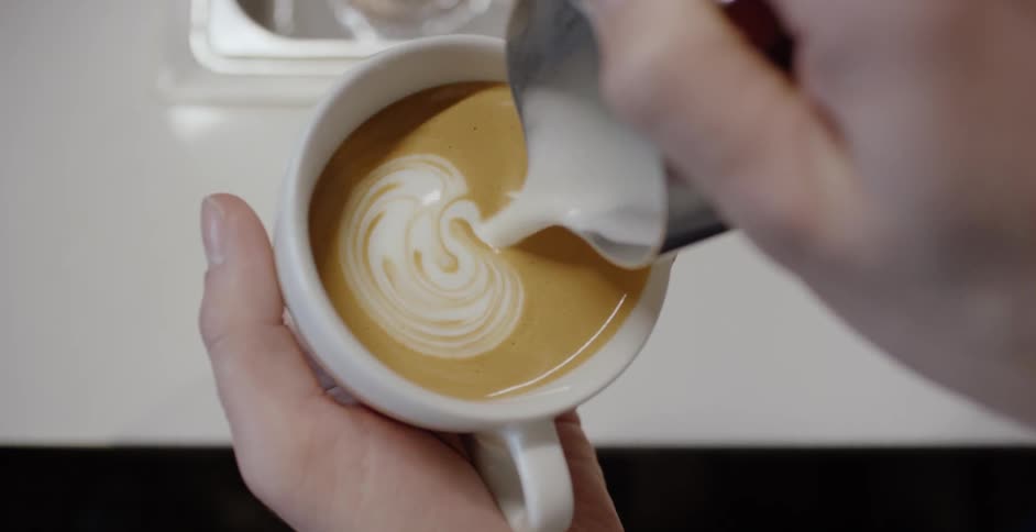 Creamer is poured into a cup of coffee