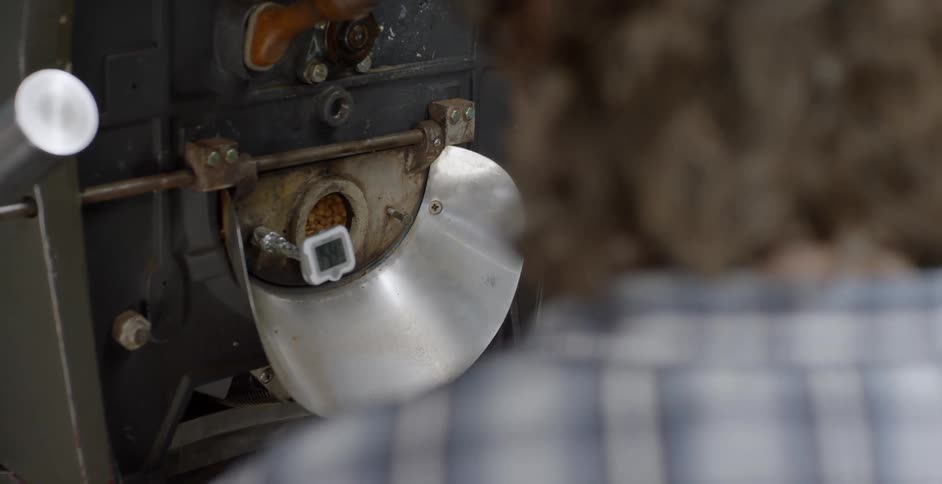 A man watches coffee beans turning in a machine