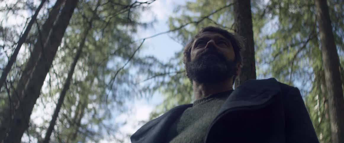 A man turns slowly in the forest