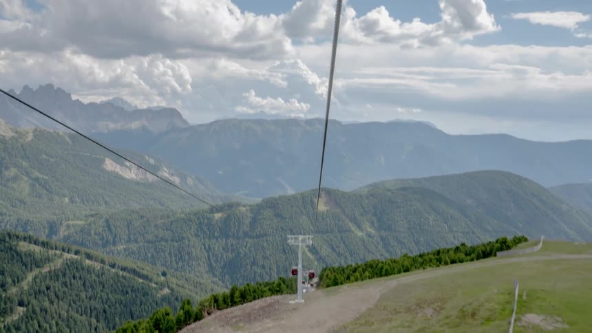 Gondolas travel up and down a lift in a mountain resort during the daytime