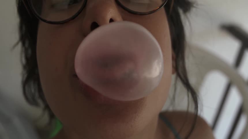 A woman blows a bubble with gum