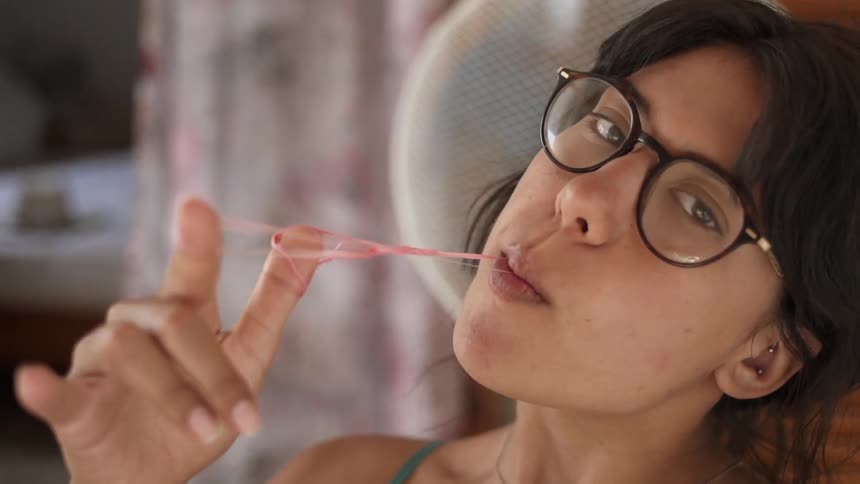 A woman plays with bubble gum in her mouth