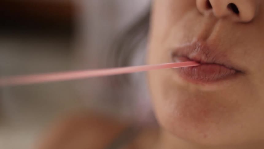 A woman is twisting bubble gum from her mouth