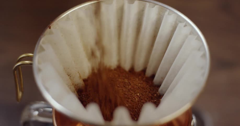 Coffee grounds are being added to a pour over coffee filter