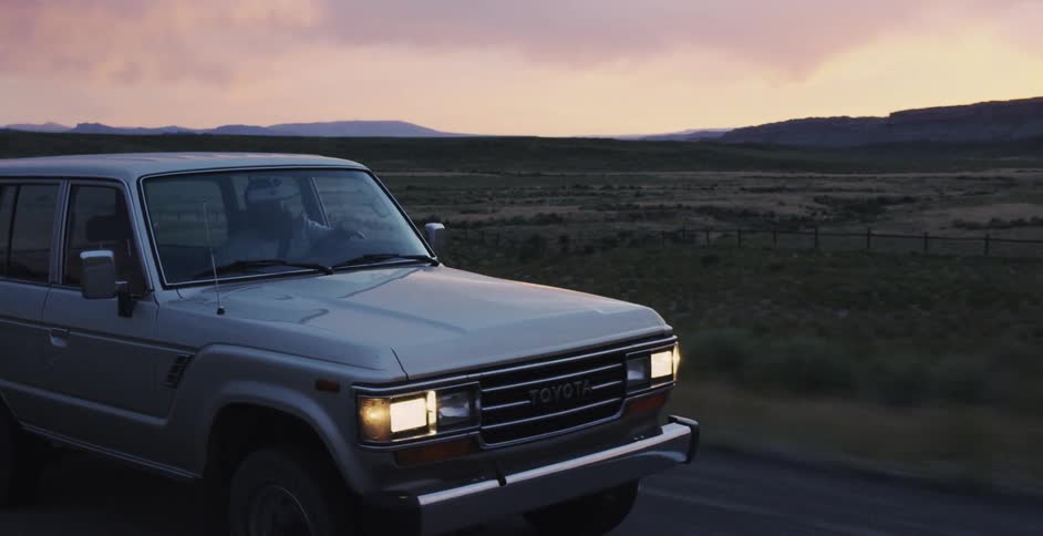 A truck is driving down the road at dawn