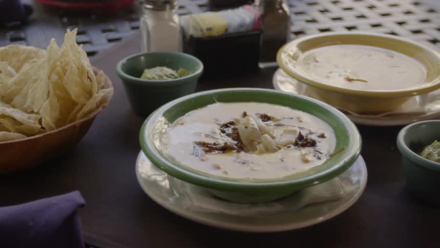The table has some soup and nachos served