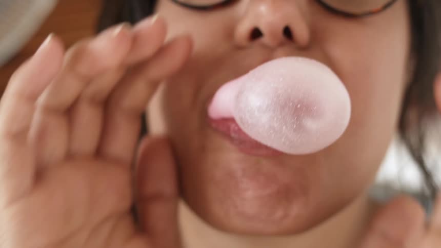 Woman blows a bubble with gum