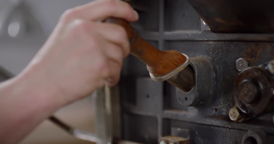A person scoops beans from a machine