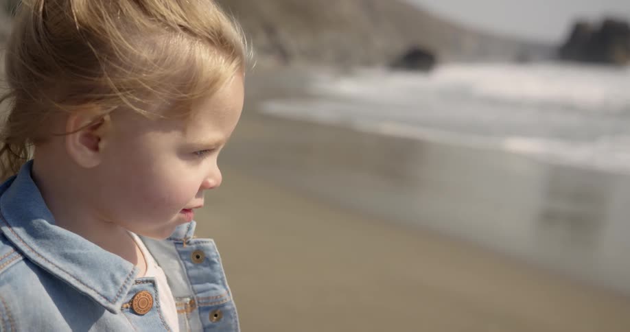 A young girl stands on the beach shore