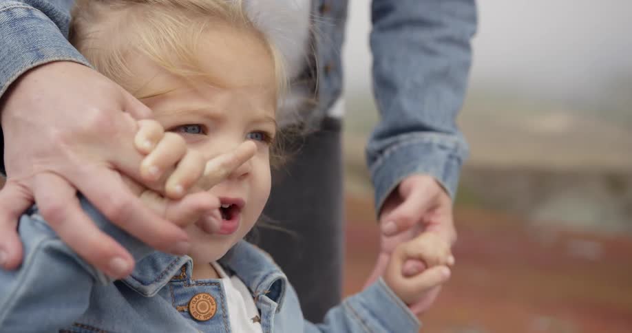 A woman holds the hands of a baby