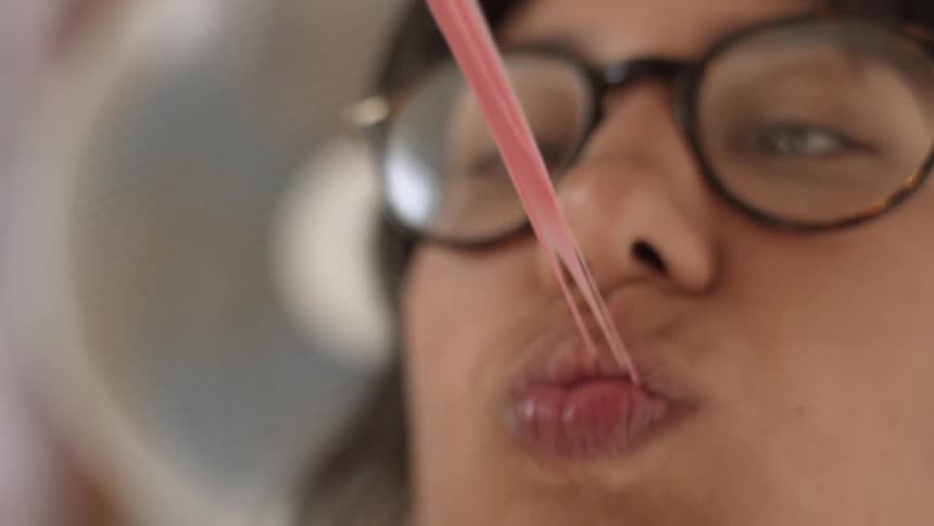 A woman chews on stretched out bubblegum