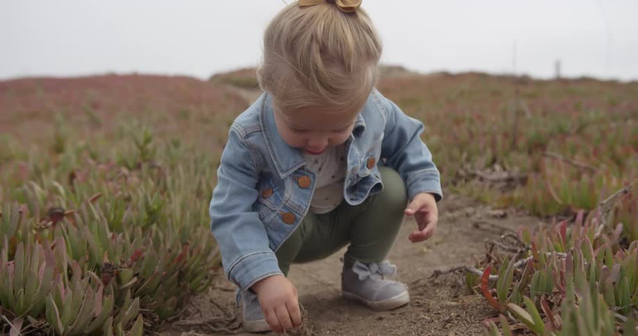 A young girl picks up dirt and debris off the ground