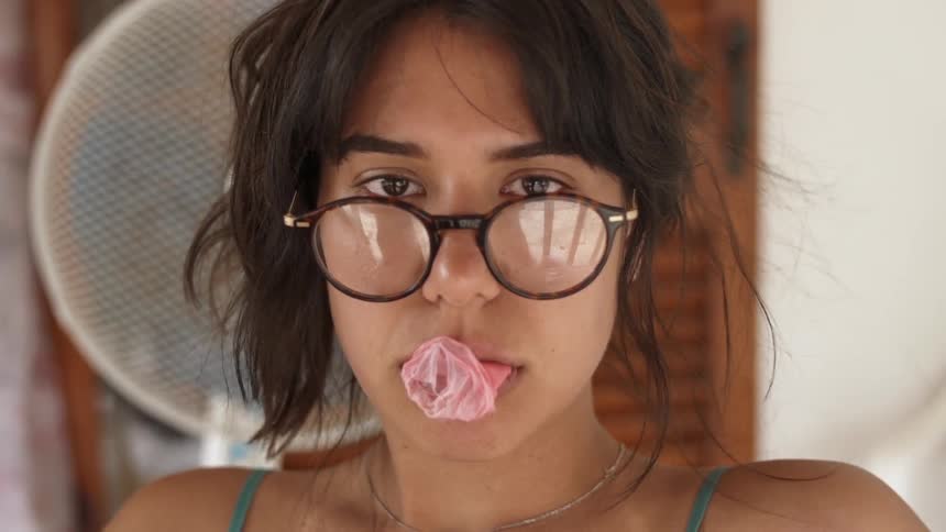 A woman stares with bubble gum hanging from her mouth