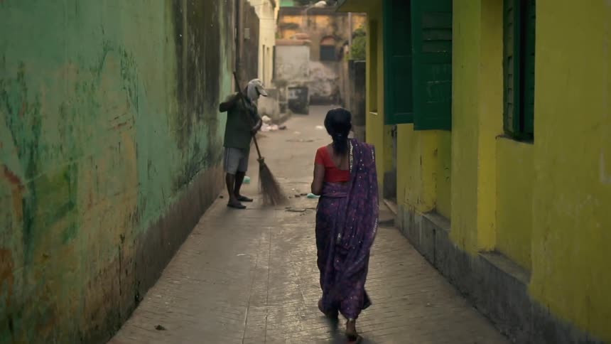 Man sweeping alleyway between two buildings